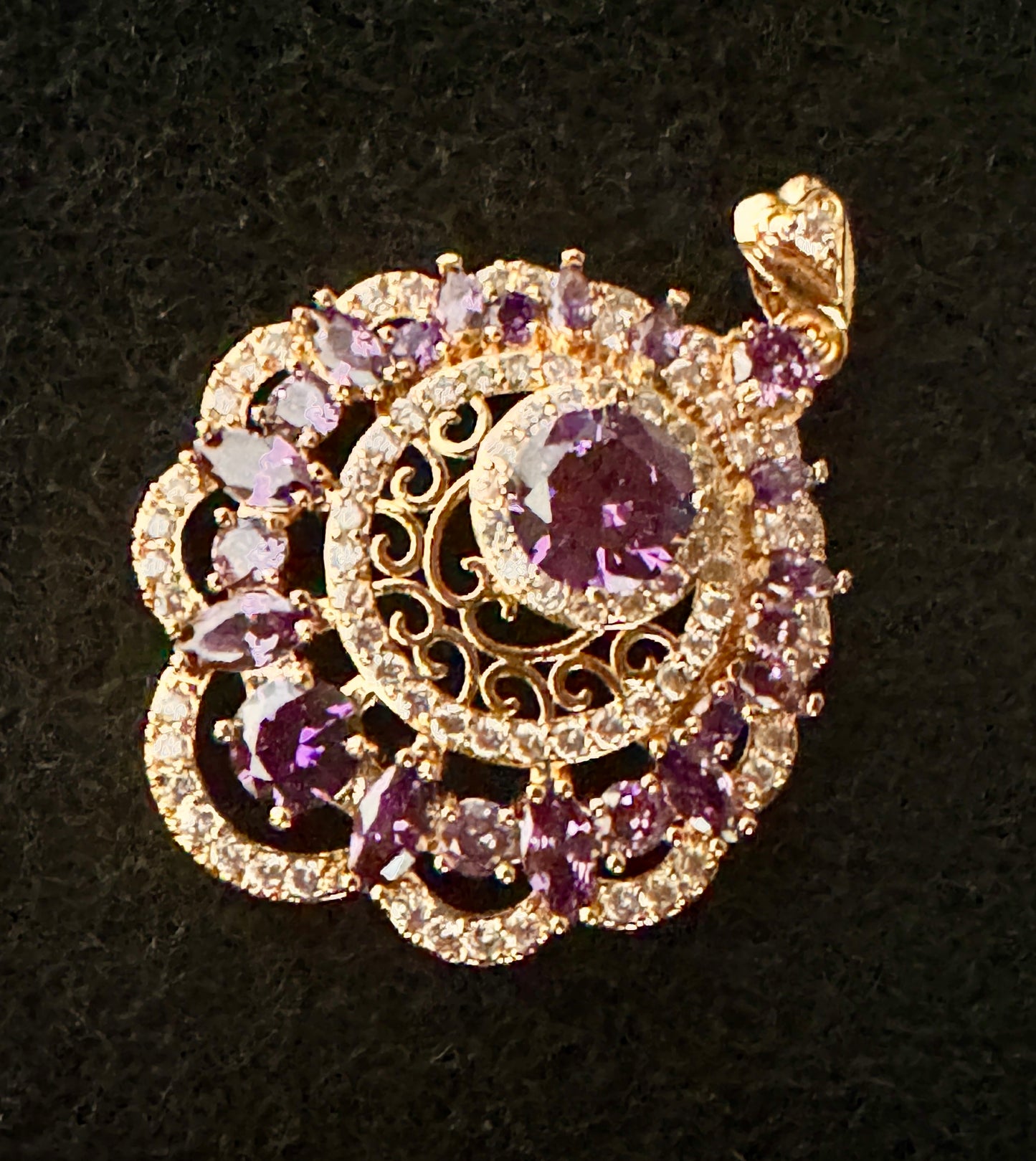Gold and purple gemstone pendant on a black background